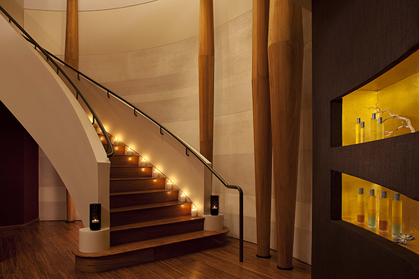 A staircase leading into a serene and luxurious spa room at The Peninsula hotel in New York. The room features elegant decor and low lighting. The image conveys a sense of relaxation and indulgence, with a focus on the luxurious spa experience at The Peninsula hotel in New York.