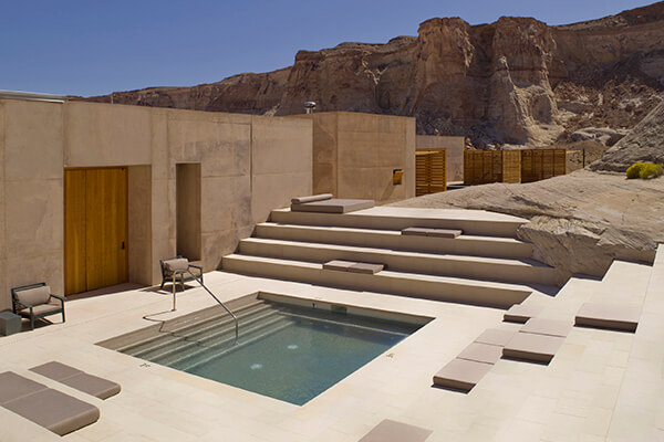A relaxing pool area amidst stunning landscape of a desert canyon in the American Southwest with a modern architectural structure made of concrete. 